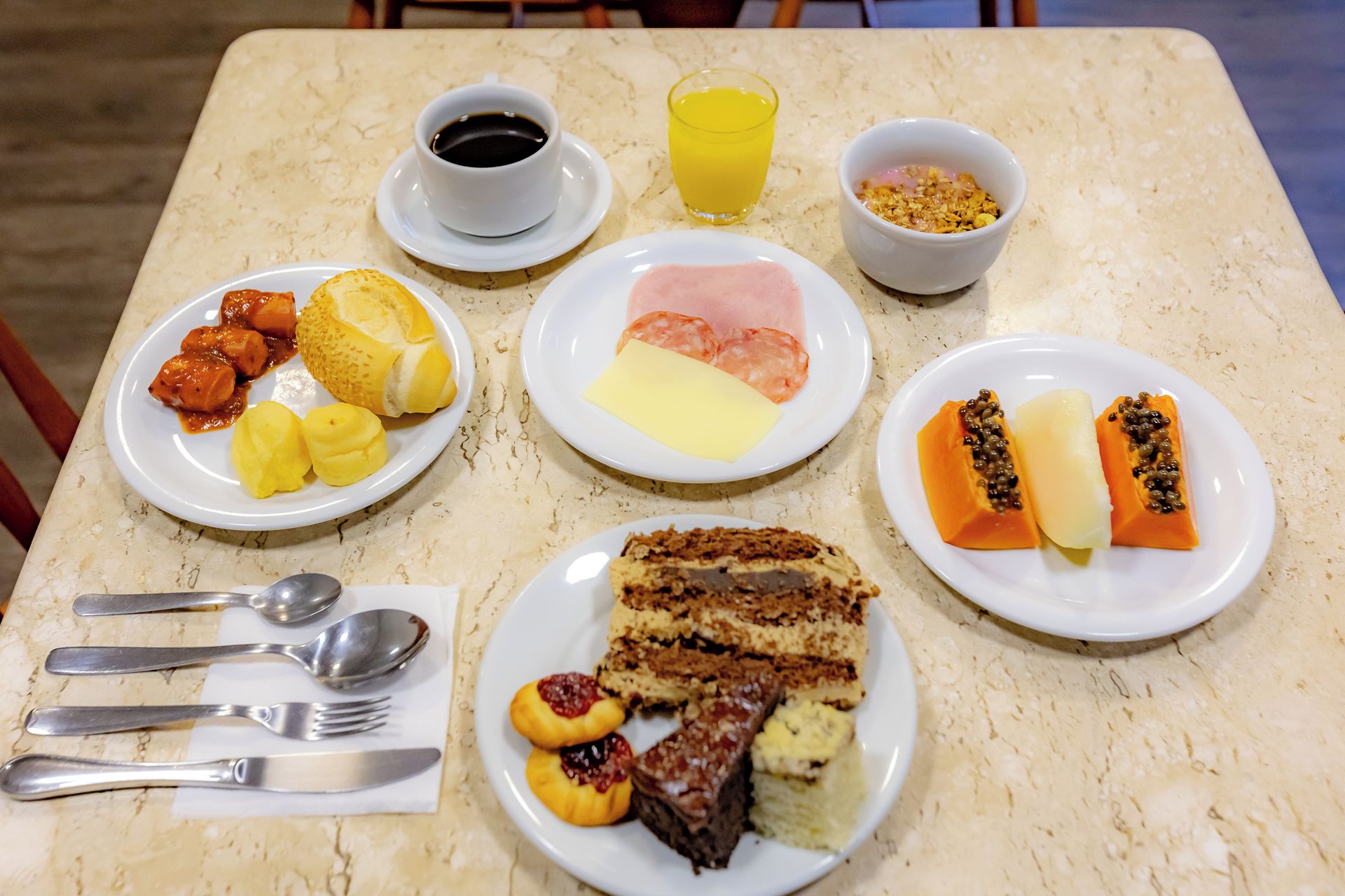 Una mesa preparada para el desayuno, con tortitas, jamón y fruta.