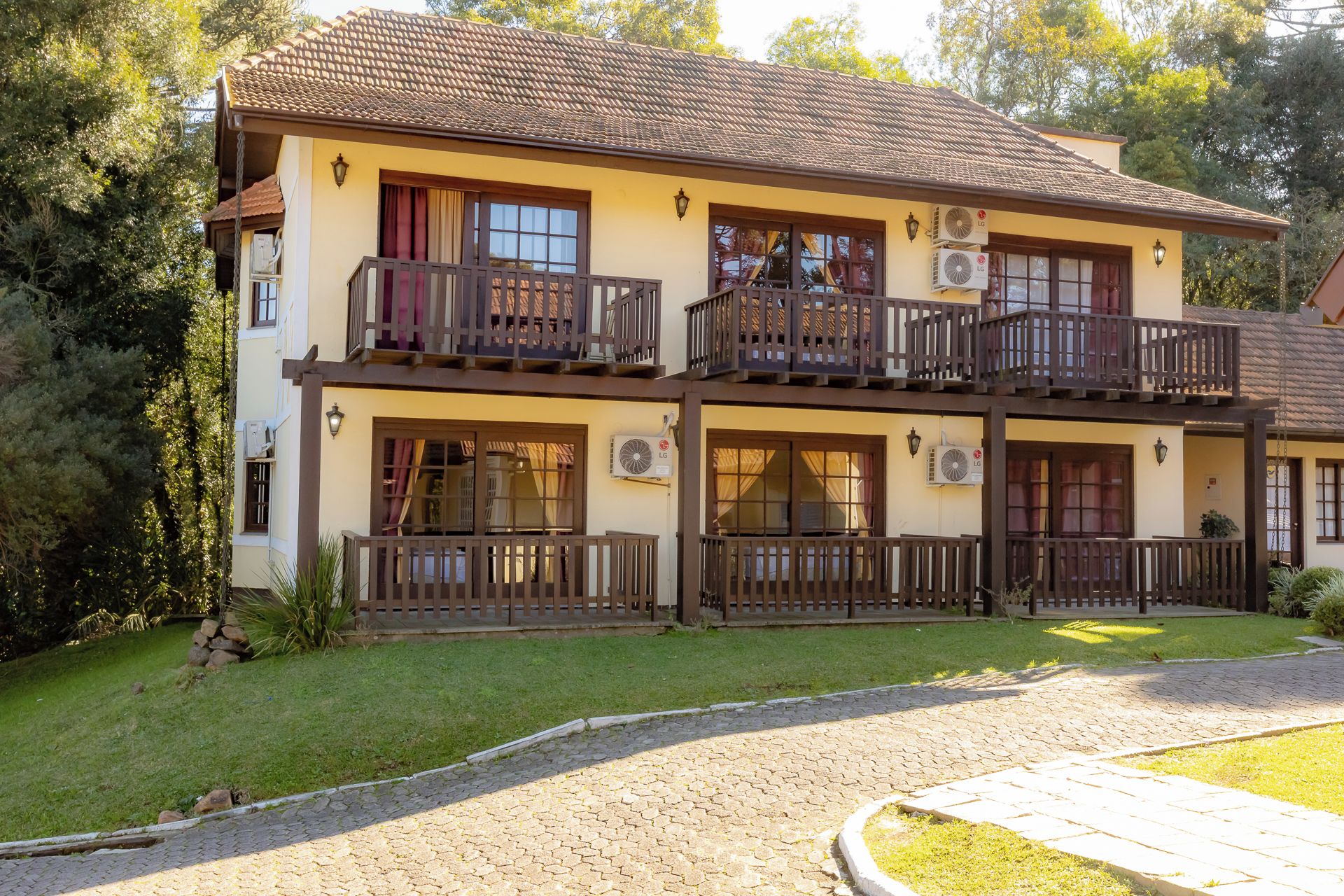 A two-story building with balconies, air conditioning units, and a paved driveway.