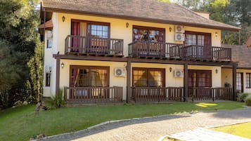 A two-story building with balconies, air conditioning units, and a paved driveway.