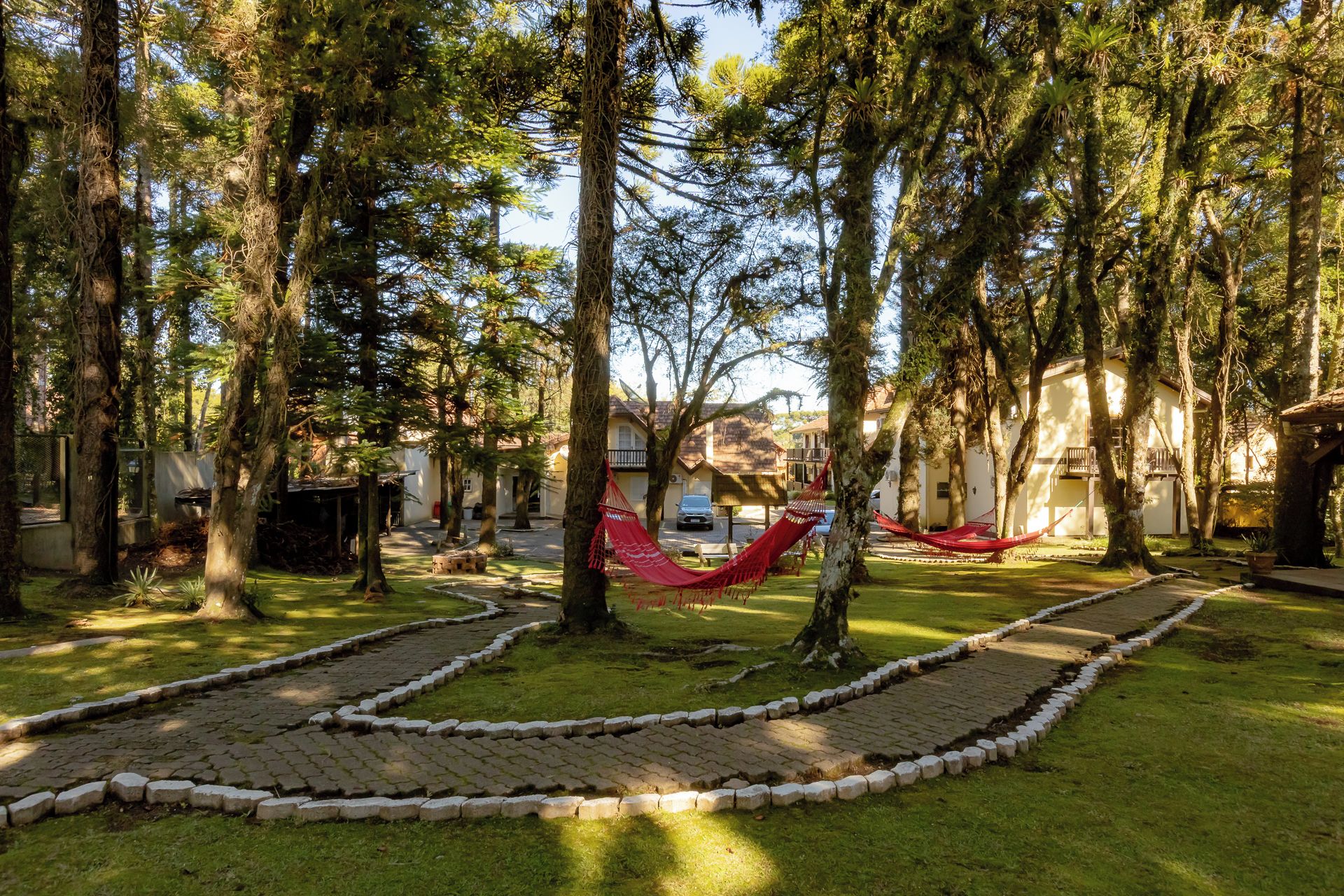 A park with a paved path, hammocks, and trees.