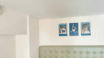 A bed with a tufted headboard, two pillows, and three framed pictures on the wall.