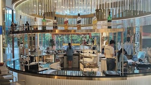 Un espace bar moderne avec un comptoir incurvé, des tabourets de bar et une variété de bouteilles d’alcool.