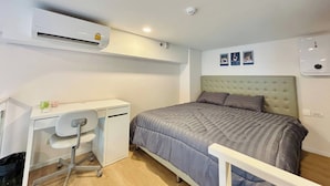 Une chambre à coucher comprenant un lit, un bureau et un appareil de climatisation.