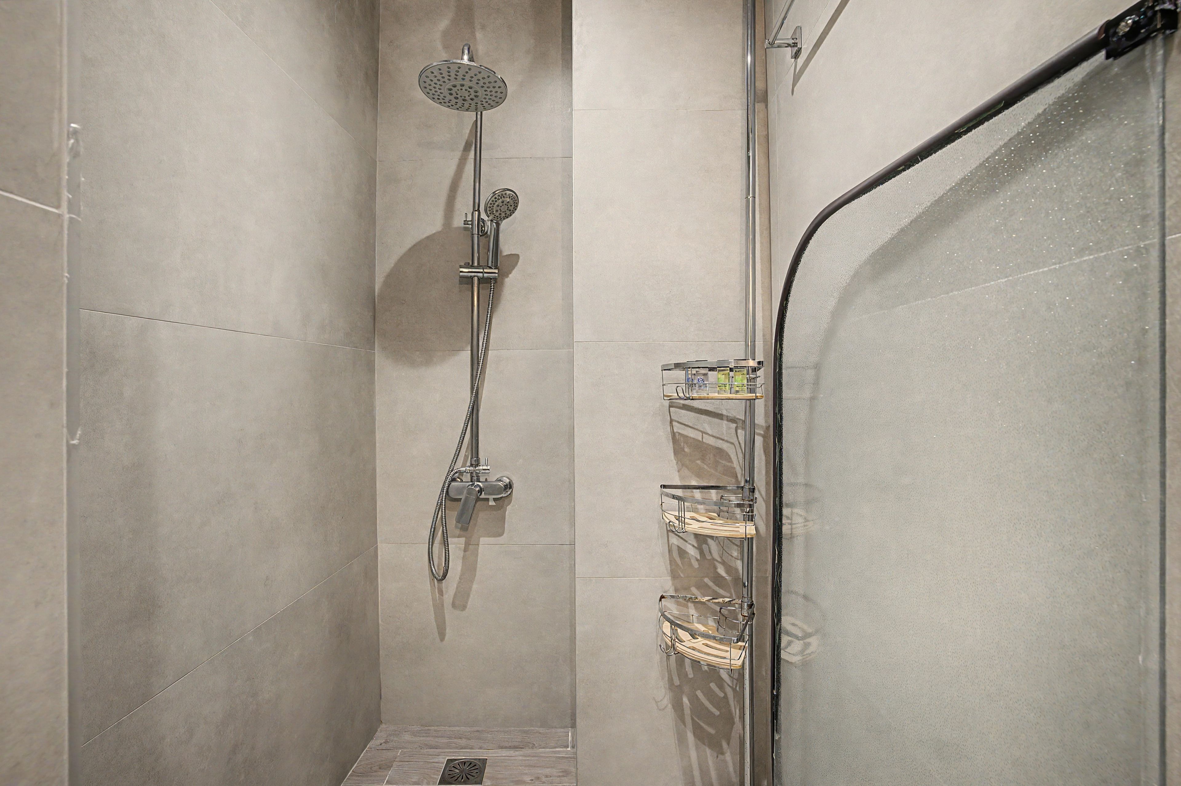 Une douche équipée d’un pommeau de douche à main et d’un robinet fixé au mur.