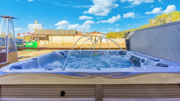 Un jacuzzi con una fuente de agua, rodeado por una zona cubierta, bajo un cielo despejado.