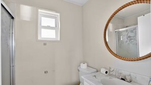 Un baño con inodoro, lavamanos, espejo y ventana.