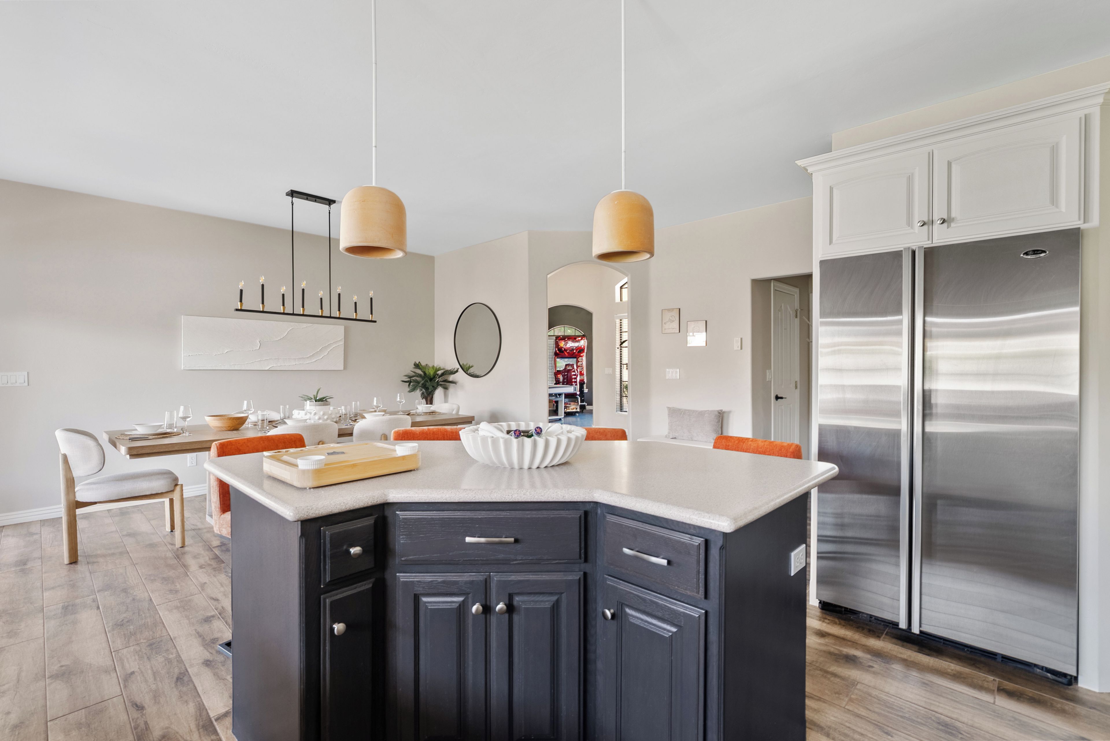 A modern kitchen with a central island, dark cabinetry, stainless steel appliances, and pendant lighting.