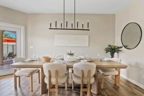 A dining room with a wooden table set for six, surrounded by six chairs. - New Luxe 5BR Resort | Pool, Pickleball | Theater (Mesa)