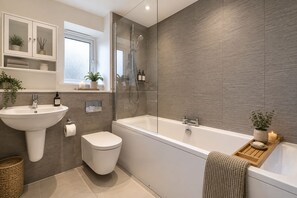 Une salle de bain moderne avec une baignoire sur pieds, un lavabo sur colonne et des toilettes.