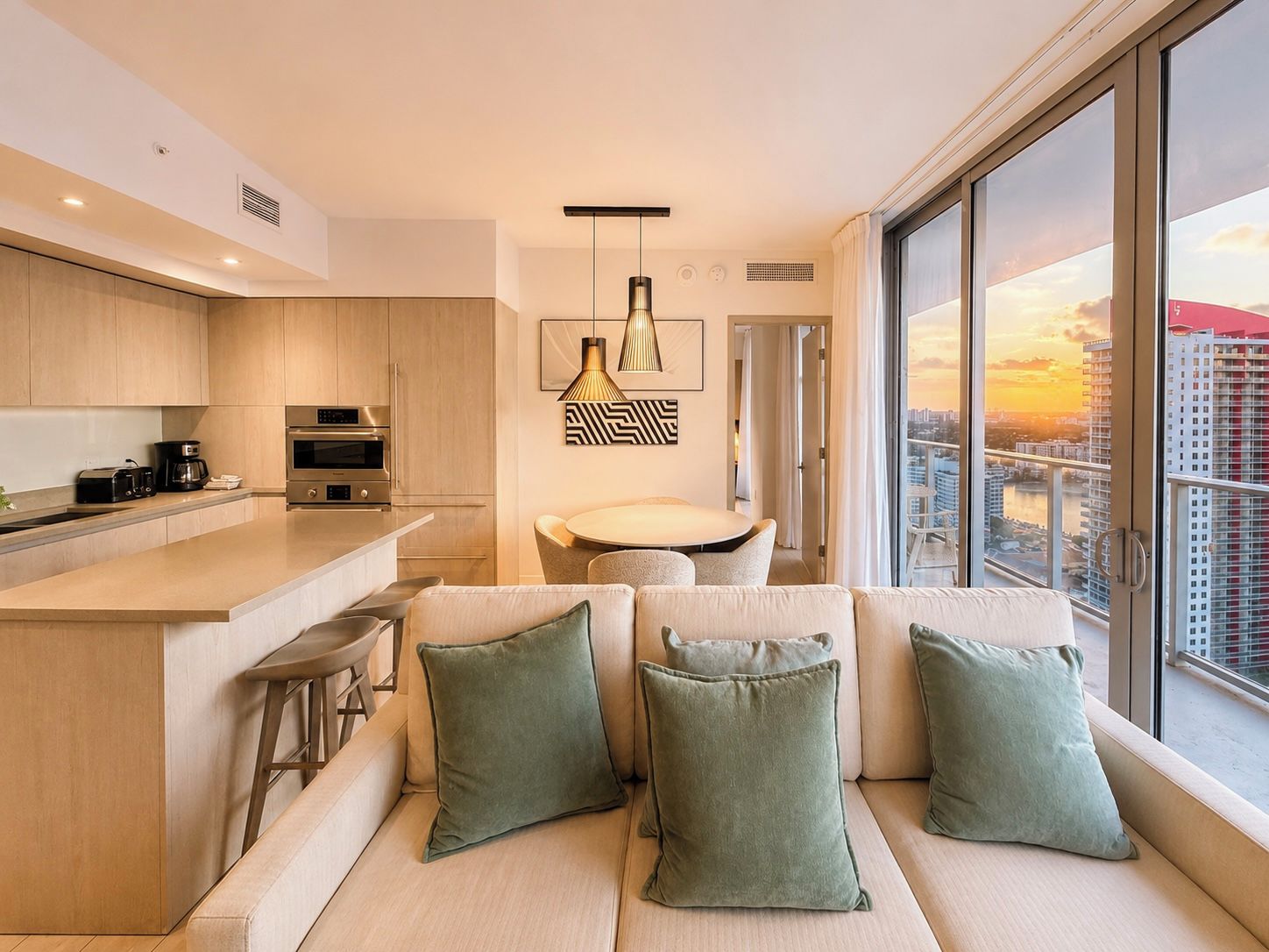A modern kitchen with a central island, a dining area with a round table, and a sofa with cushions.