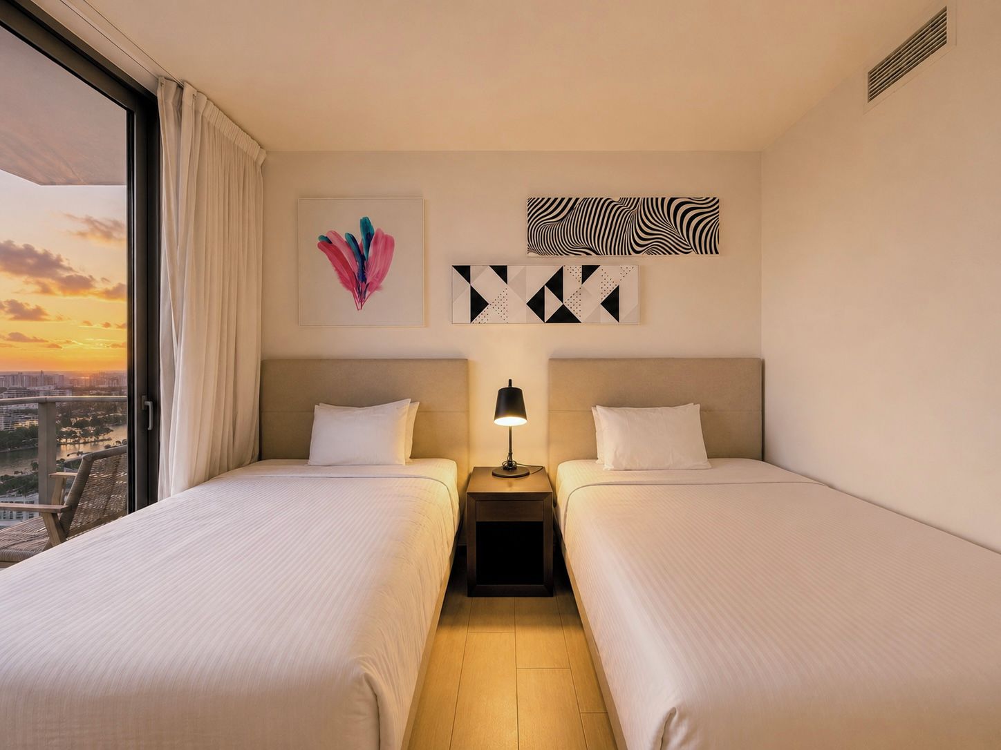 Ein Hotelzimmer mit zwei Betten, einem Nachttisch mit Lampe und einem Kunstwerk an der Wand.