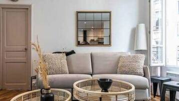 A living room with a sofa, two side tables, a wall-mounted mirror, and a door.