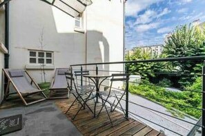Ein Balkon mit Holzboden, Metallgeländer und einem Tisch mit Stühlen.
