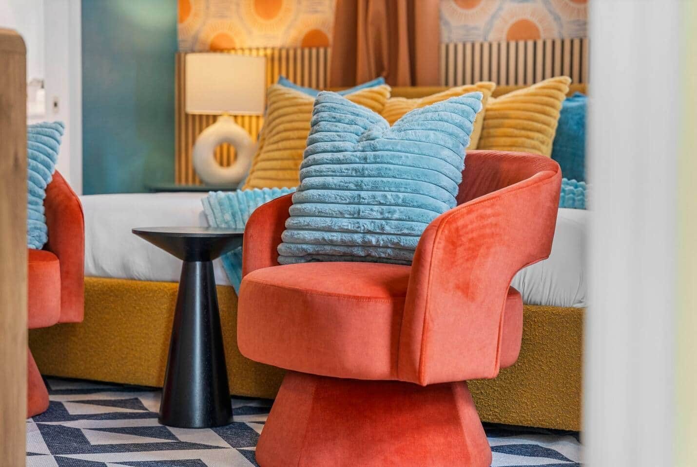 Ein modernes Schlafzimmer mit einer Couch und einem Sessel, einem Nachttisch und einem gemusterten Teppich.