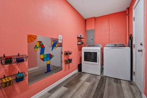 Ein Waschraum mit zwei Waschmaschinen, einem Spiegel und farbenfrohen geometrischen Verzierungen an der Wand.