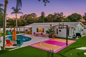 A residential property with a swimming pool, a basketball court, and a patio area with outdoor seating. - Playcation Oasis (Pinellas County)