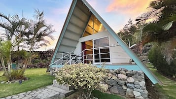 A triangular-shaped building with a stone foundation, a glass door, and a small porch area.