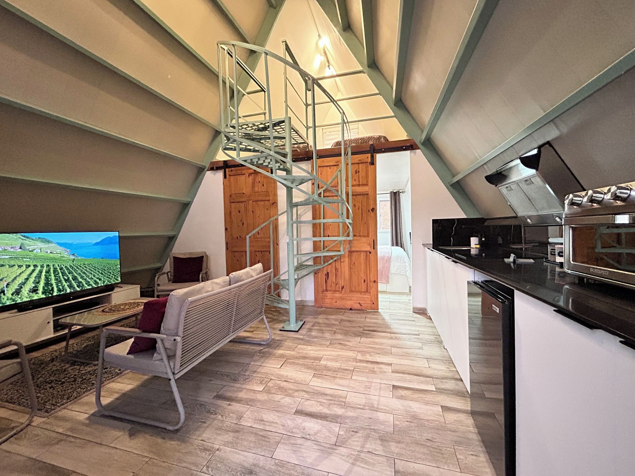 A modern interior with a kitchen, dining area, and a staircase leading to an upper level.