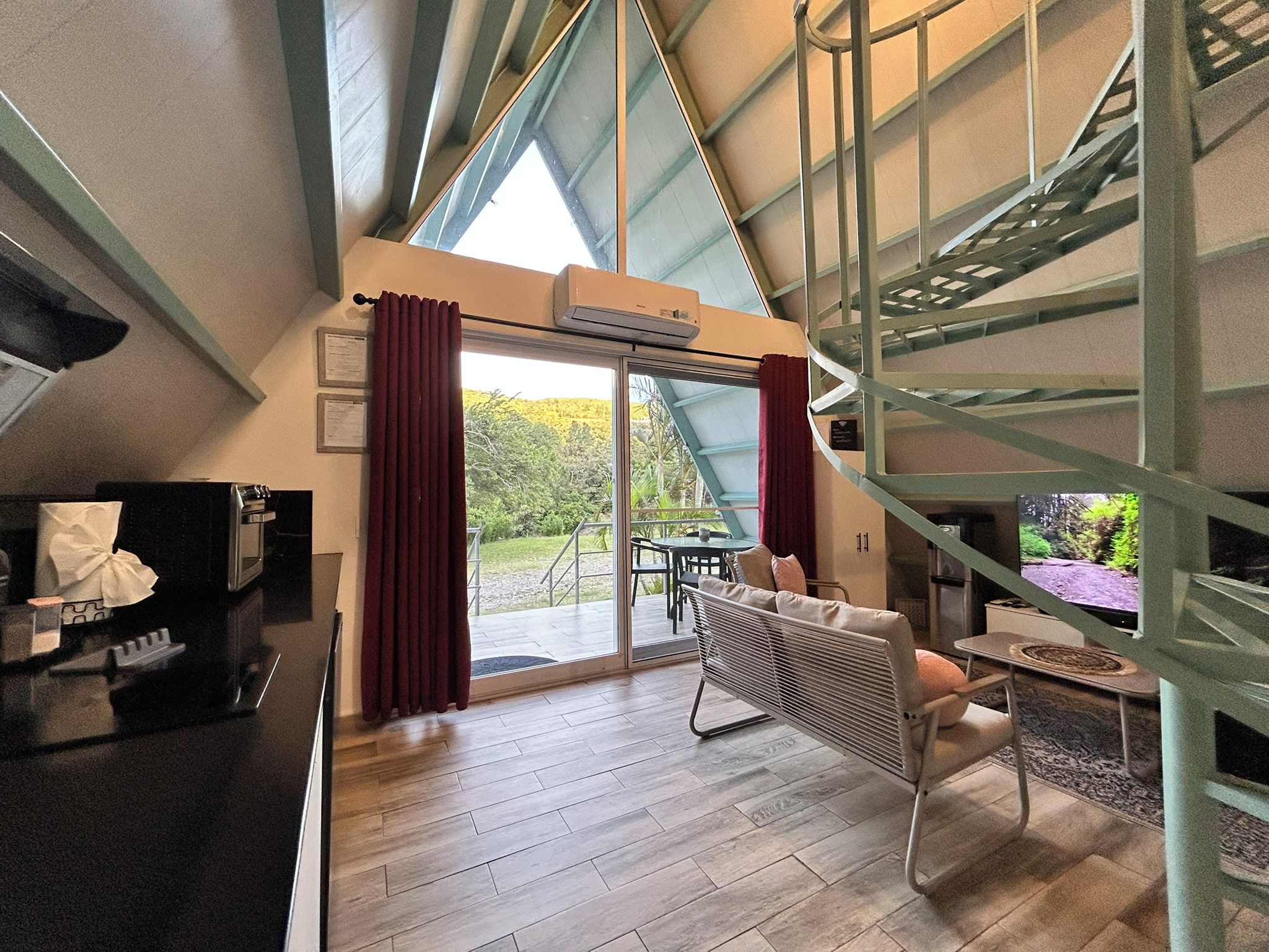 Un interior moderno con área de cocina, una mesa de comedor con sillas y un amplio ventanal que da a un patio exterior.