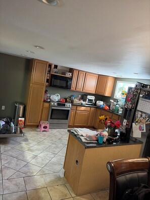 A kitchen with wooden cabinets, a microwave, an oven, and a refrigerator. - 3-bedroom house in charming Walnutport with AC for relaxing stays (Walnutport)