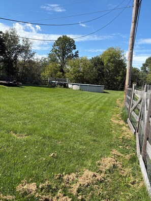 A grassy field with a wooden fence, a metal gate, and a utility pole. - 3-bedroom house in charming Walnutport with AC for relaxing stays (Walnutport)