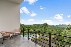 Un balcón con sillones de mimbre y vistas a un paisaje exuberante.