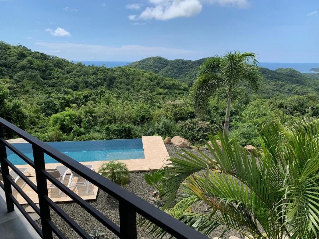 Una piscina con vistas a un paisaje verde exuberante y el océano.