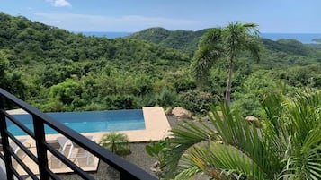 Una piscina con vistas a un paisaje verde exuberante y el océano.