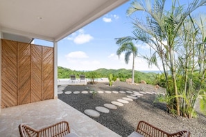 A modern outdoor seating area with a view of a landscaped garden and distant hills. - Villas Vivo (Potrero)