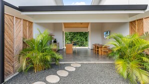 Un interior moderno con comedor, cocina y vistas al exterior.