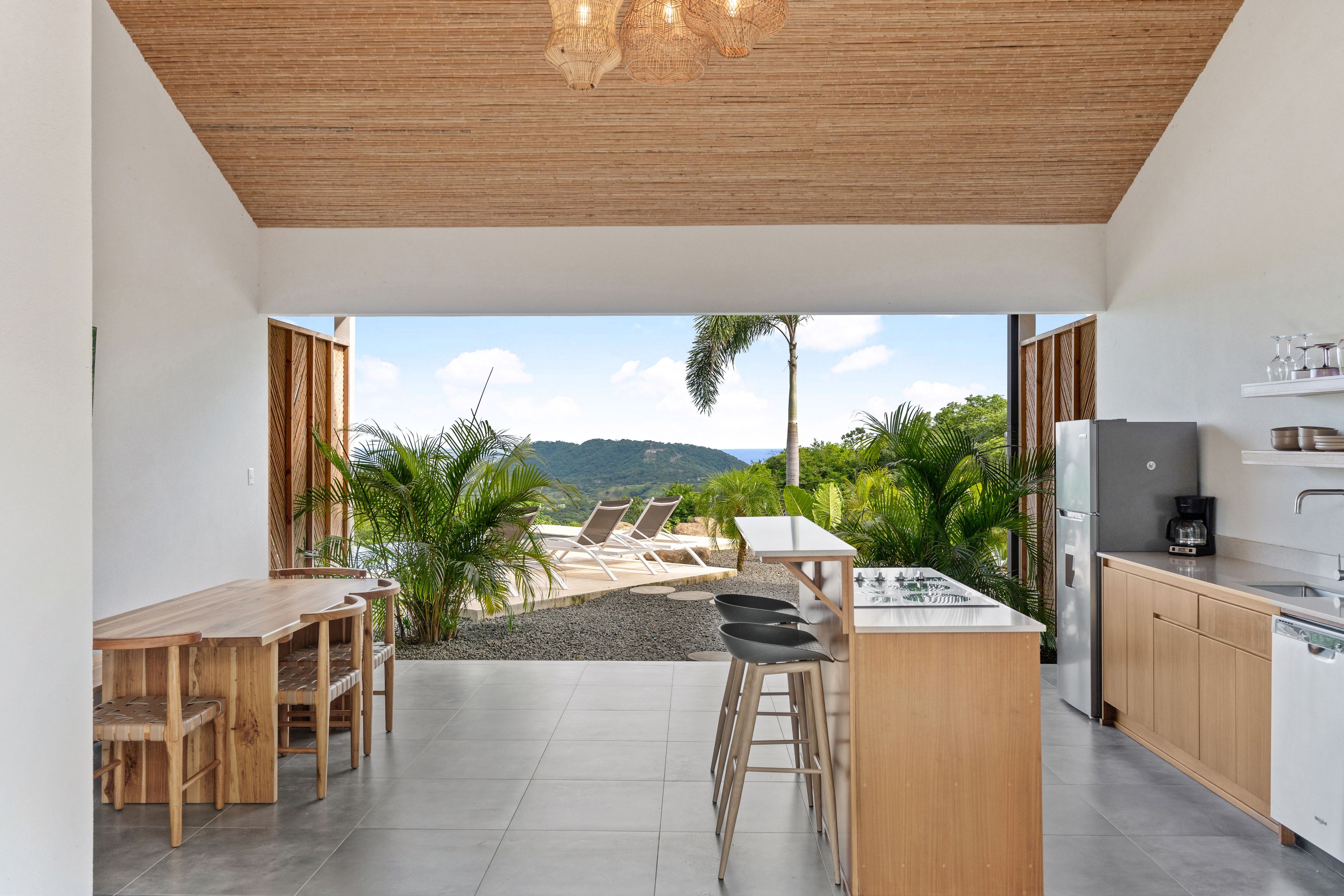 A modern kitchen with a view of a pool and palm trees.