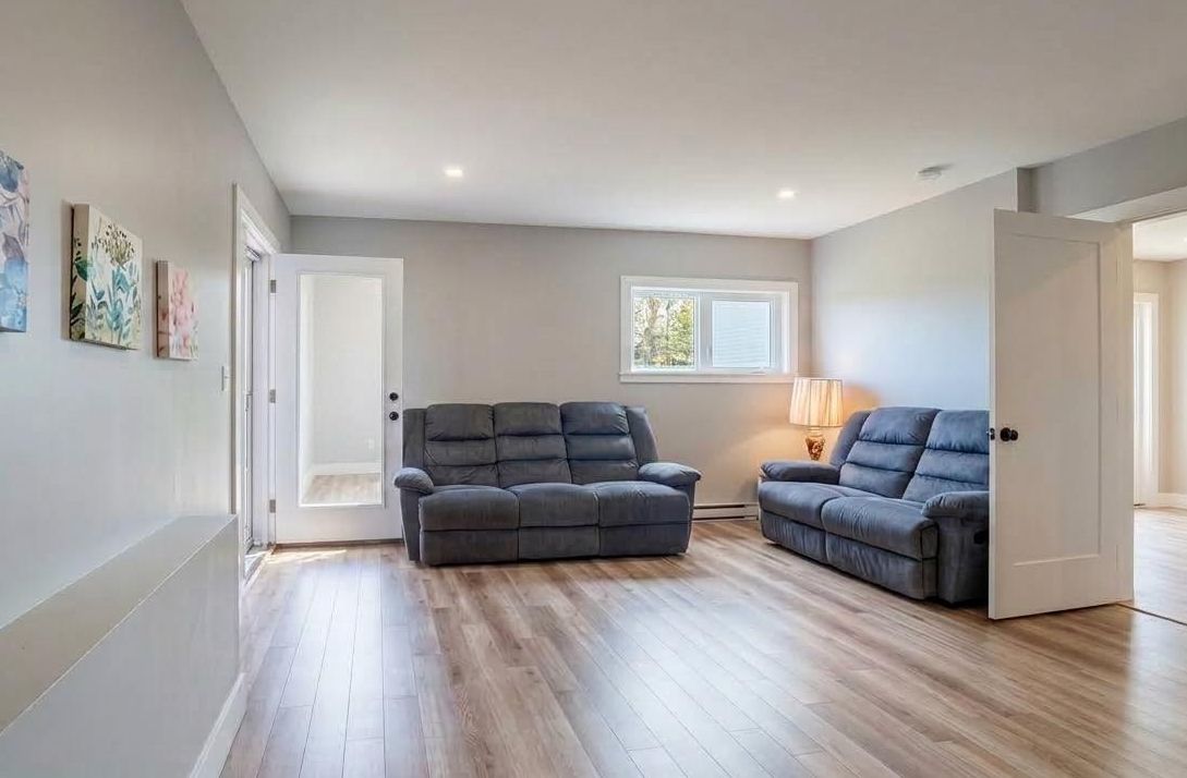A room with a grey sofa, a lamp, and a window.