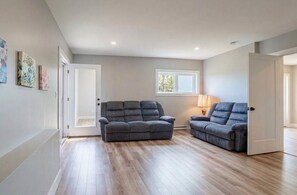 A room with a grey sofa, a lamp, and a window.