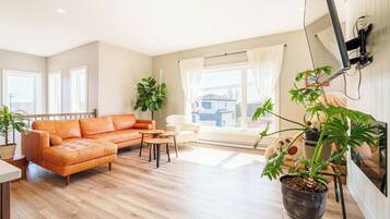 A living room with a sofa, a coffee table, and potted plants.