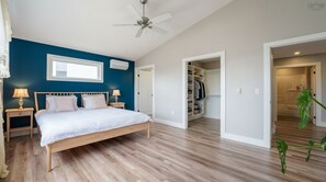 A bedroom with a bed, bedside tables, a ceiling fan, a window, and a closet.