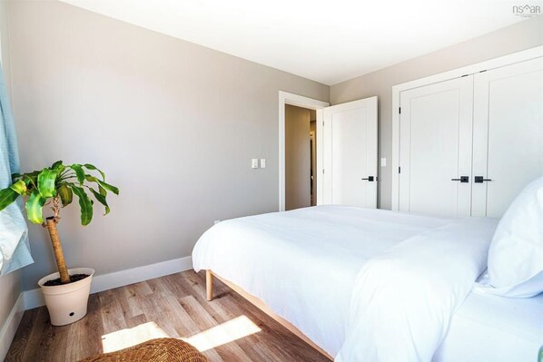 Un dormitorio con una cama, una planta en maceta y una puerta que da a otra habitación.