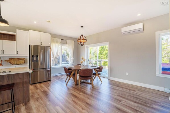 A modern kitchen with a stainless steel refrigerator, wooden cabinets, and a dining area with a round table and chairs.