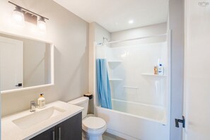 A bathroom with a sink, toilet, and shower area.