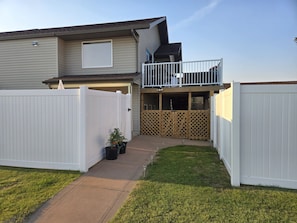 A residential property with a fenced backyard, a balcony, and a covered patio area.