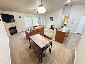 Uma sala de estar ampla com lareira, área de jantar e cozinha com balcão.