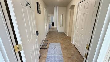 Un pasillo con puertas blancas, alfombra gris y suelo de baldosas.