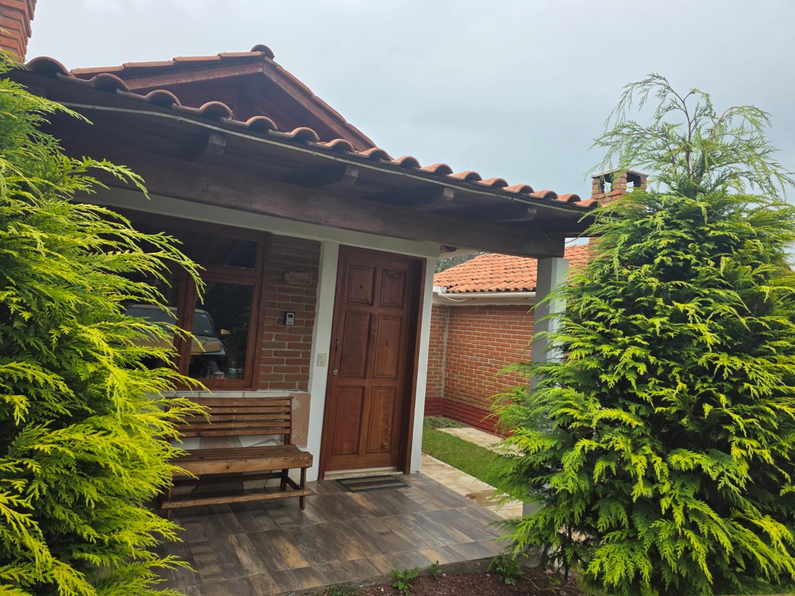 A residential property with a brick facade, a wooden door, and a bench outside.