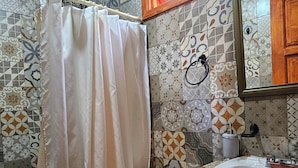 A bathroom with a shower curtain, toilet, sink, and a window above the mirror. - Cabañas JH (Huasca)