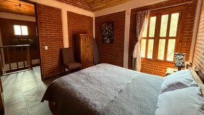 A bedroom with a bed, a chair, a wardrobe, and a window with curtains. - Cabañas JH (Huasca)