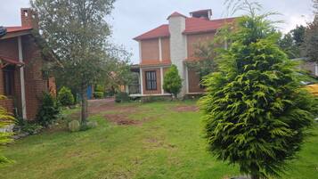Una propiedad residencial con una casa de ladrillo, un césped bien cuidado y un gran árbol de hoja perenne.