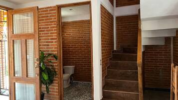 A staircase with wooden steps leading to a second floor, adjacent to a brick wall and a door with glass panels.
