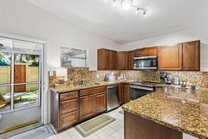 A modern kitchen with granite countertops, stainless steel appliances, and wooden cabinets. - Livingston Hideaway • Walk To Lake Eola • Hot Tub (Orlando)