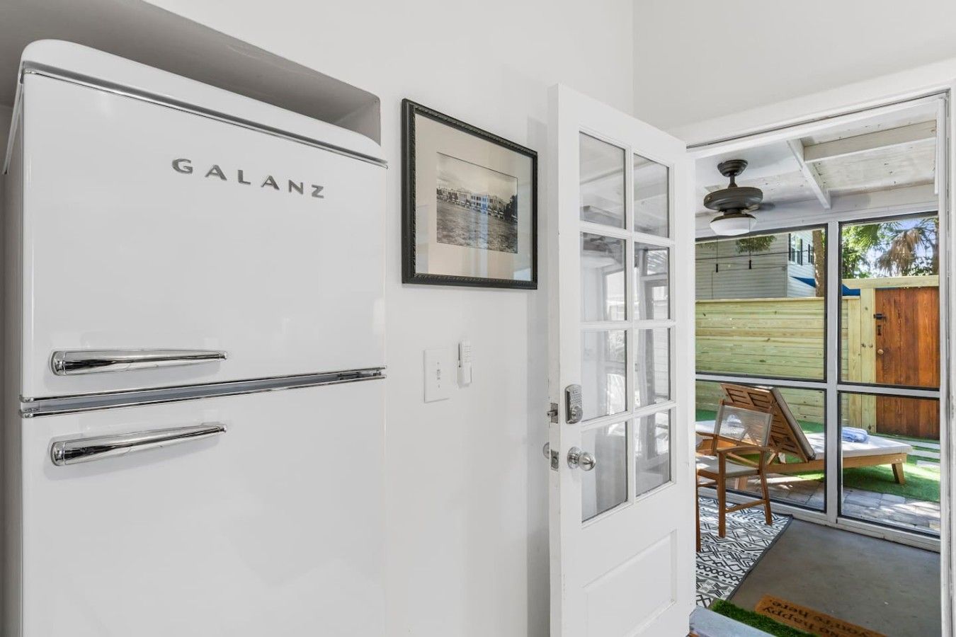 A white Galanz refrigerator with two drawers, a door with a glass panel, and a framed picture above it.