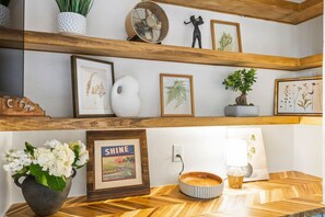 A wooden shelf with framed botanical prints, a potted plant, and a decorative fan. - Livingston Hideaway • Walk To Lake Eola • Hot Tub (Orlando)