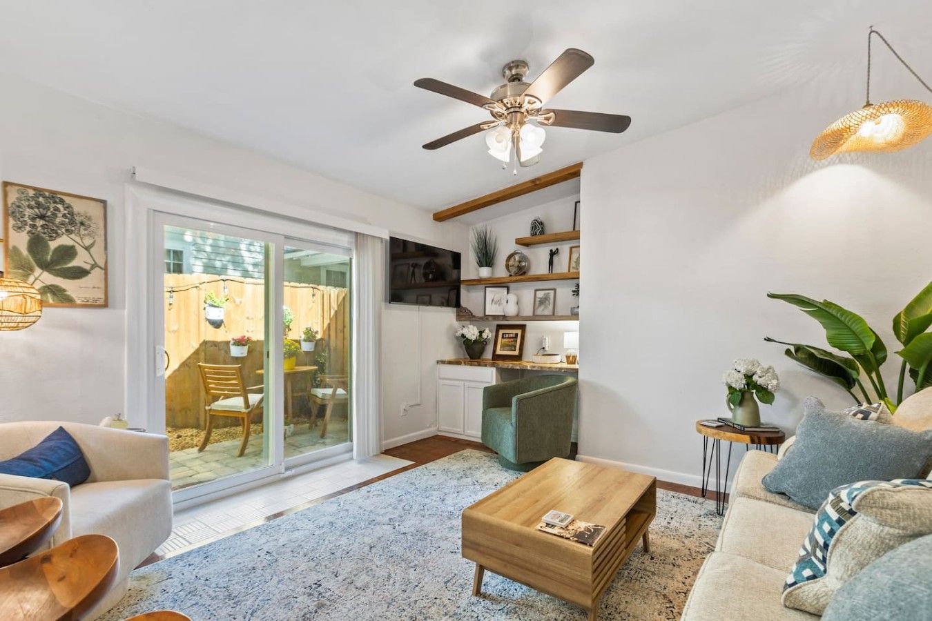 Un salon avec un ventilateur de plafond, une table basse, un canapé et un téléviseur fixé au mur.